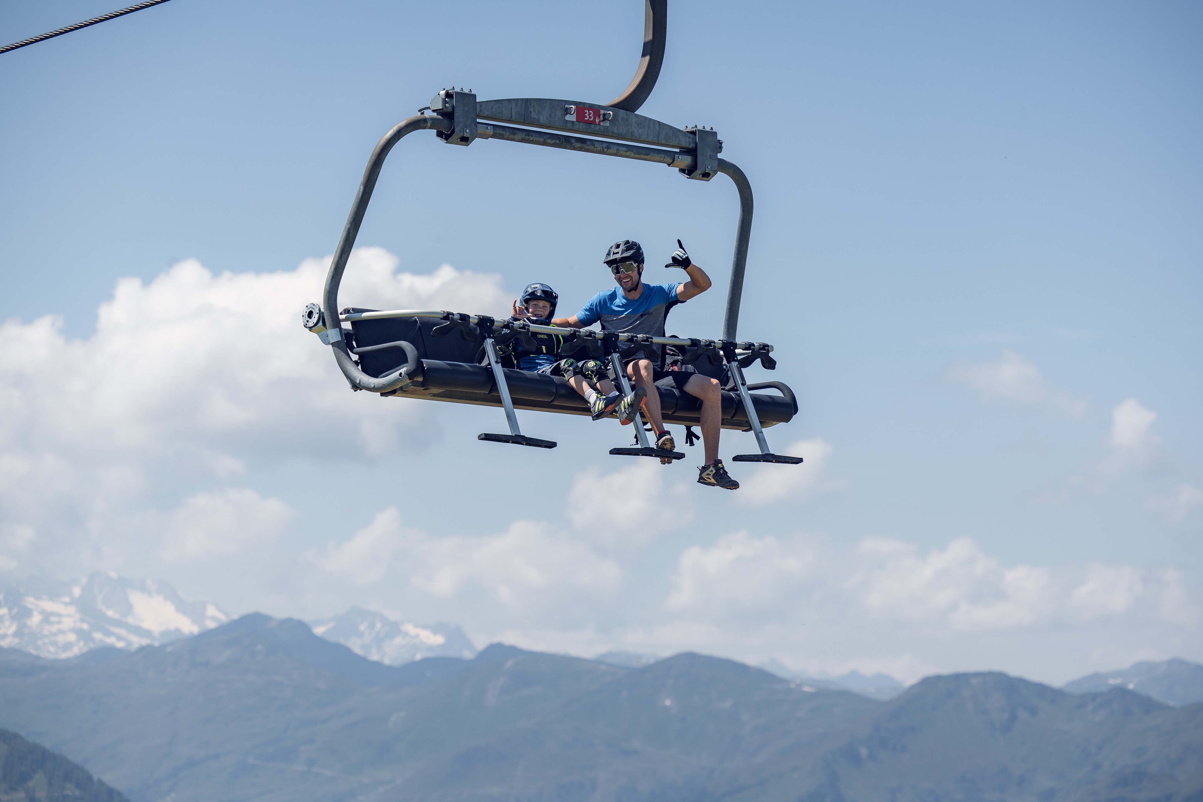Ein Erwachsener und ein Kind nutzen die Sonnenrastbahn für den Aufstieg zum Trail. Der Lift ist mit speziellen Halterungen für den Mountainbike-Transport ausgestattet.