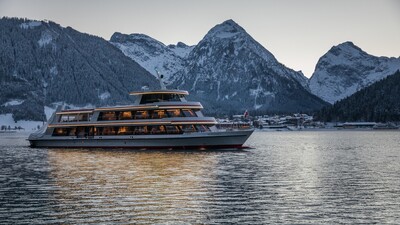 The MS Achensee cruising over Lake Achensee on a winter evening. In the background of this photo is the village of Pertisau and the Karwendel mountains.