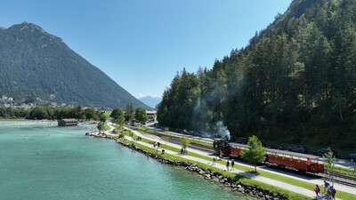 Die Luftaufnahme zeigt die Achenseebahn an der Haltestelle Seespitz im Sommer. Im Hintergrund ist die Ortschaft Maurach am Achensee zu erkennen.