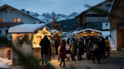 Besucher genießen die stimmungsvolle Atmosphäre des Adventsmarkts beim Dorfhaus in Steinberg am Rofan bei Nacht.