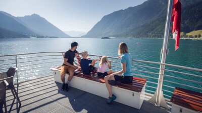 A family enjoying a boat trip with the Achenseeschifffahrt, enjoying the water and the beautiful natural surroundings.