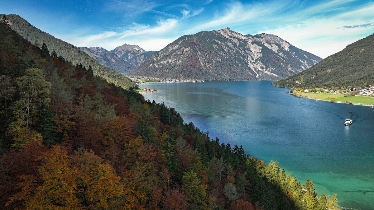 Autumn view of Lake Achensee with a boat heading towards the Seespitz landing stage.