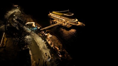 This photo captures the onshore Christmas market and the Scholastika pier in Achenkirch illuminated at night.