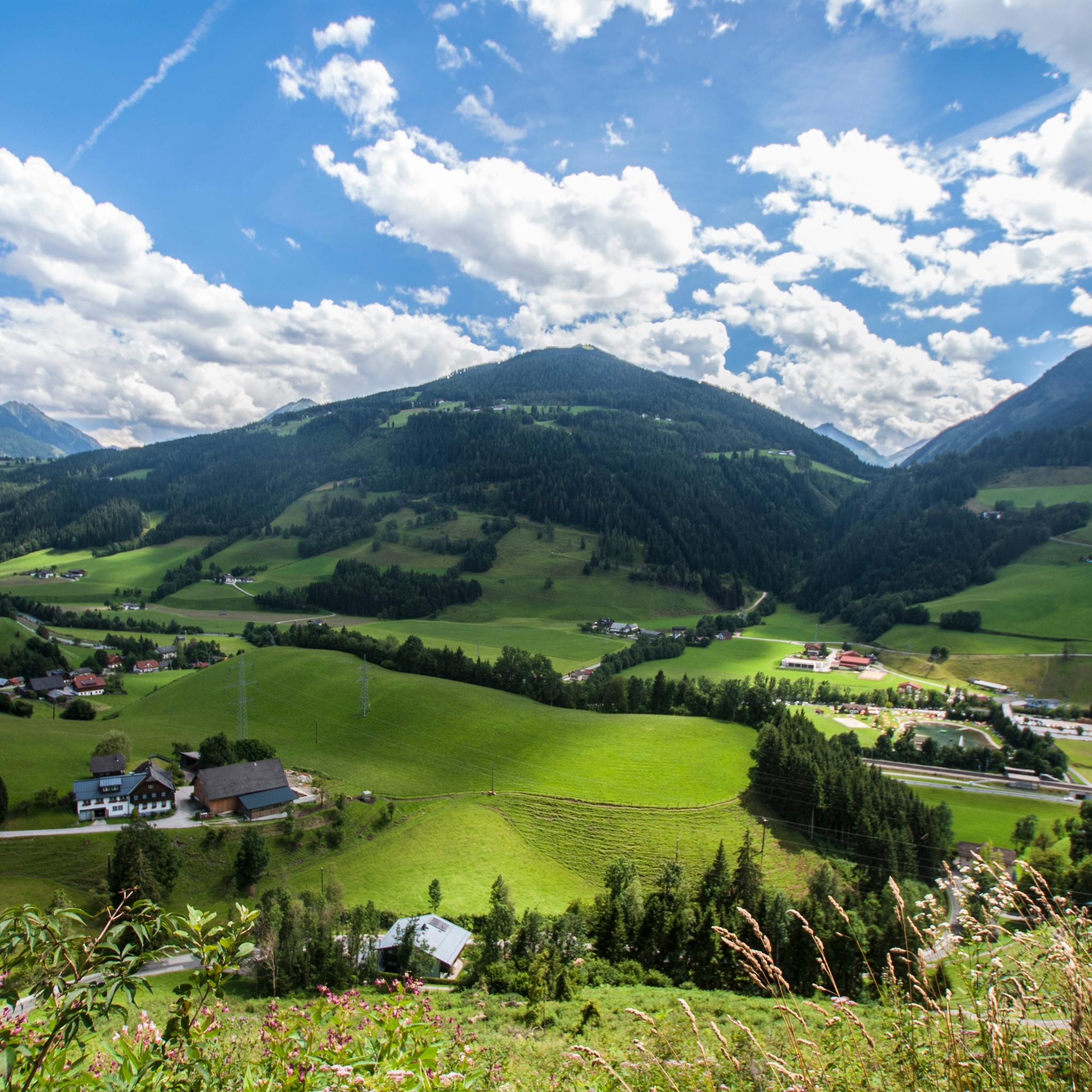 Aussicht von der Abergrunde über die alpine Kulturlandschaft in Richtung Pichl mit der Hochwurzen im Hintergrund.
