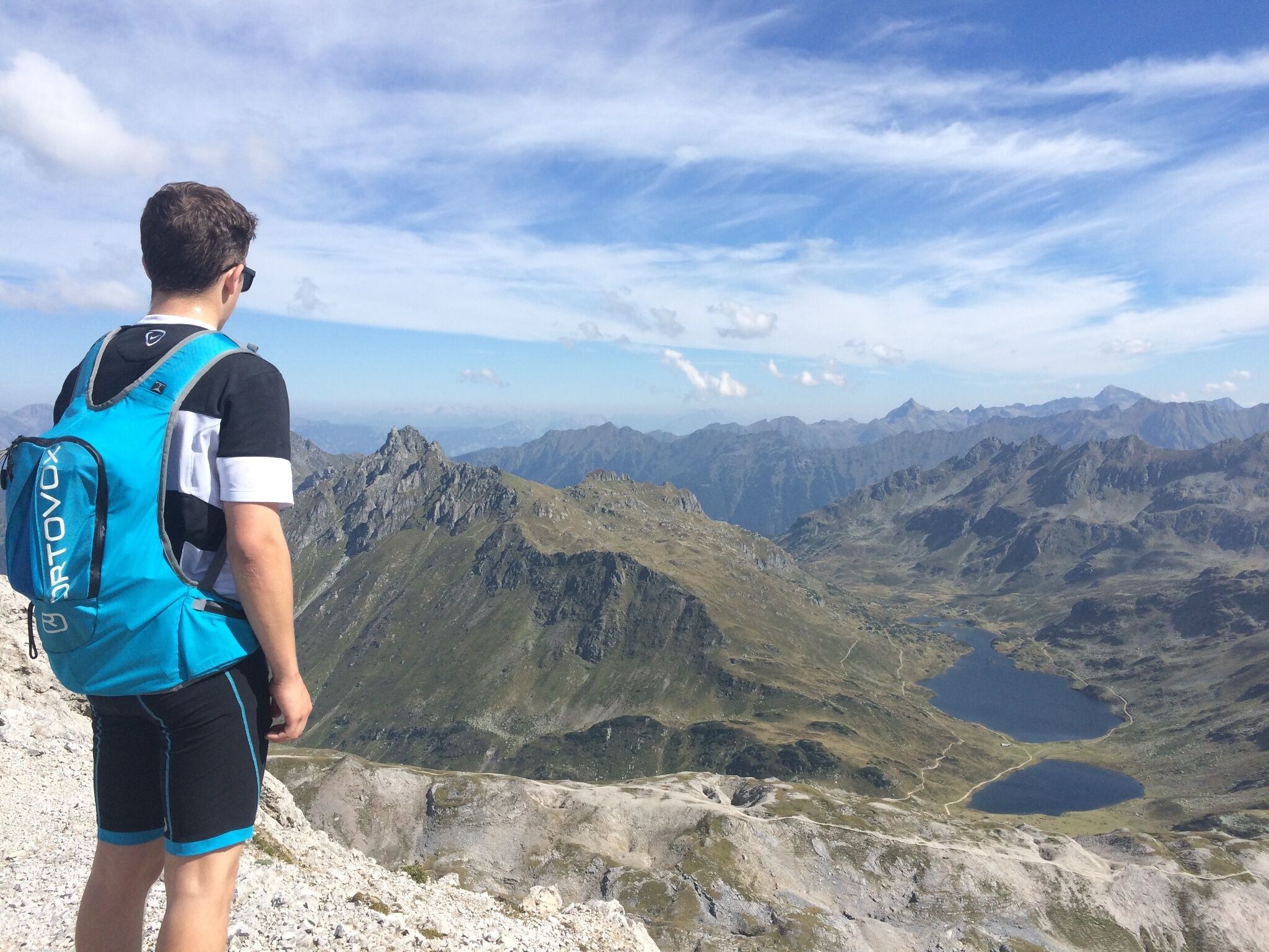 Ein Wanderer steht auf der Lungauer Kalkspitze. Im Tal sind die Giglachseen inmitten der alpinen Gebirgslandschaft zu sehen.