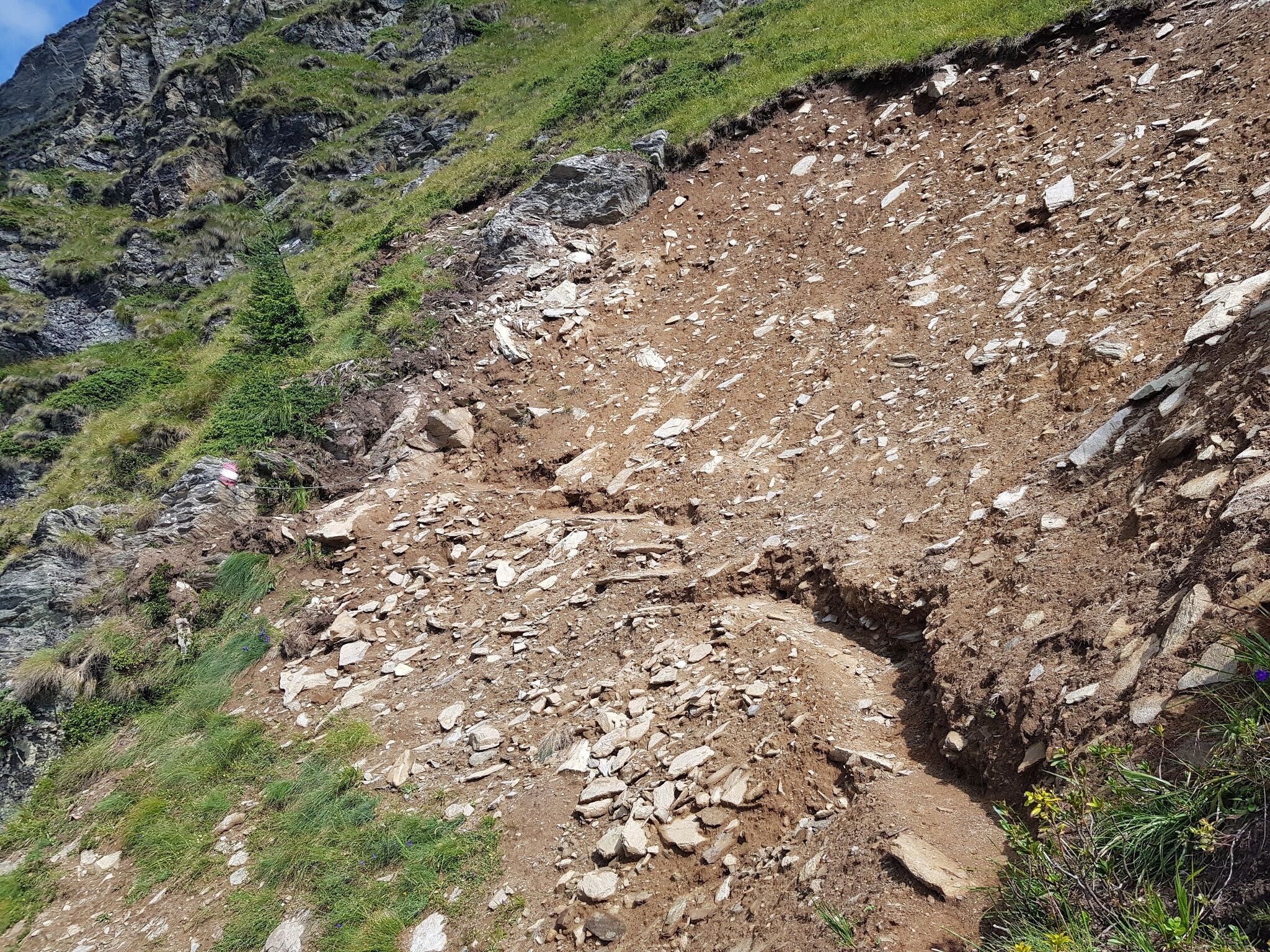 Die Aufnahme zeigt einen frisch angelegten Wegabschnitt unterhalb des Krahbergzinken. Der Pfad führt durch loses Erdreich und Gestein an einem alpinen Steilhang.